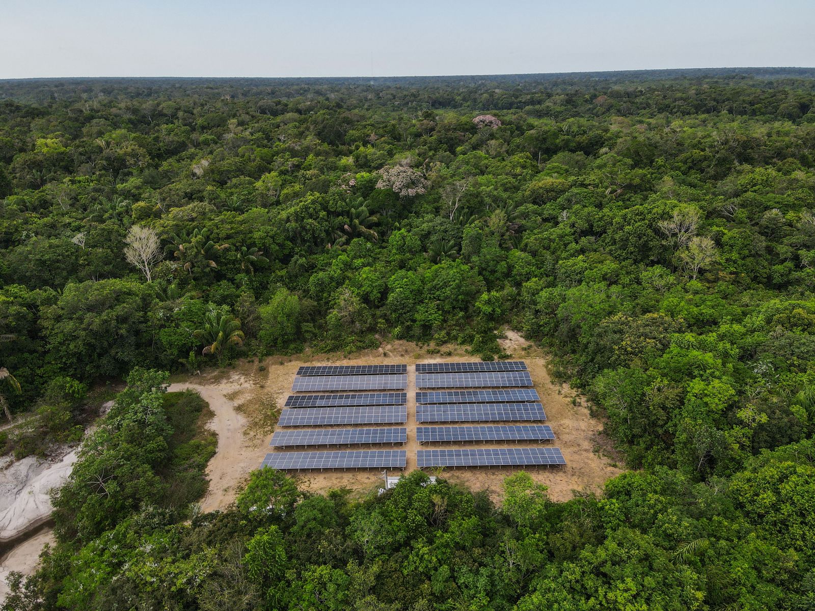 Vista aérea de uma usina de painéis solares instalada numa clareira no meio da floresta amazônica