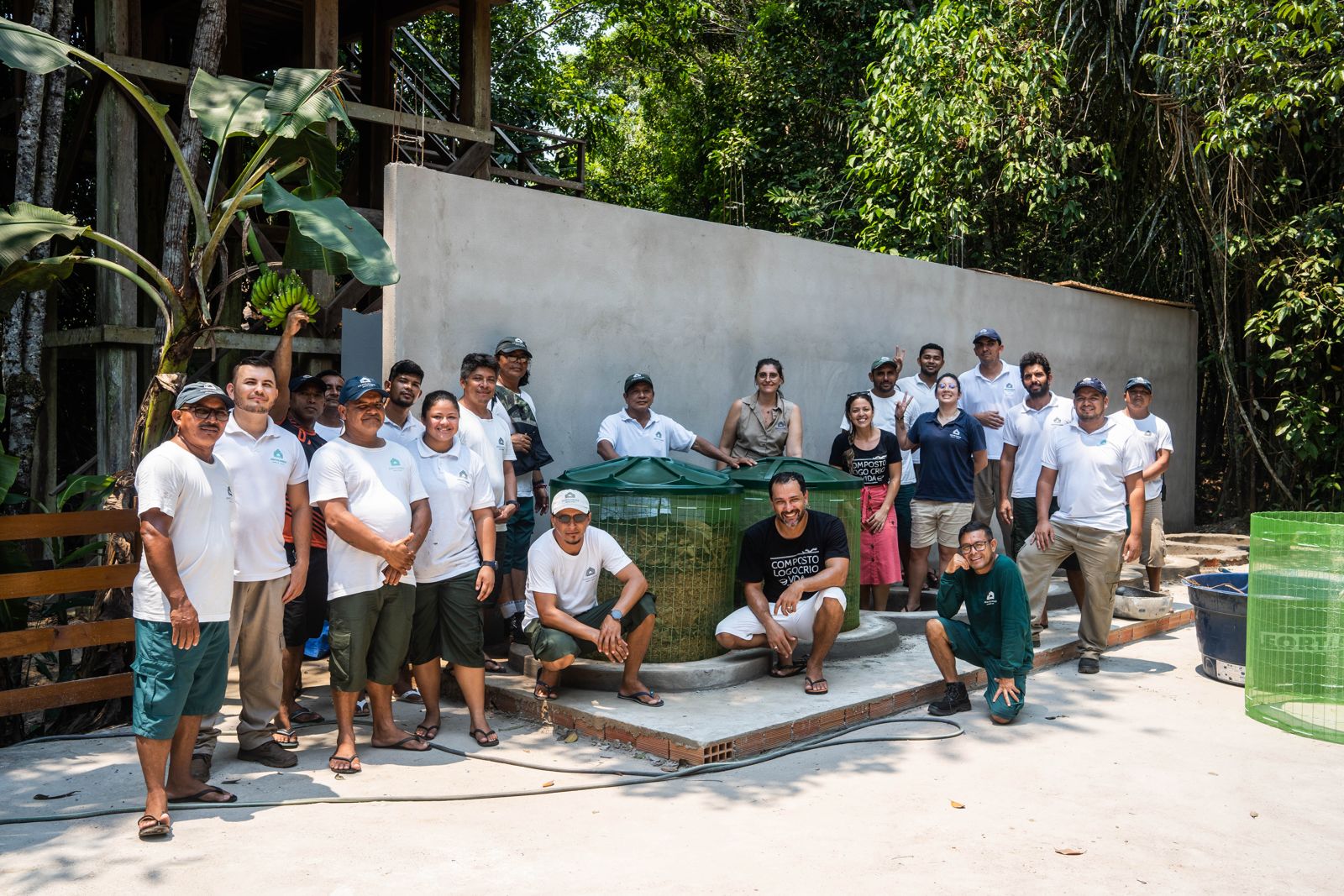 Mãos com luvas reviram resíduos orgânicos dentro de uma composteira durante a oficina com a Yby