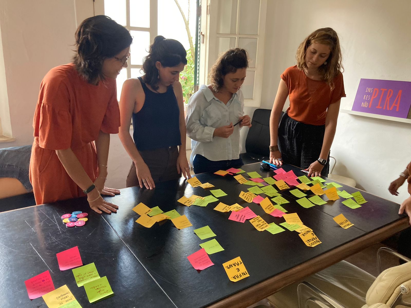 Equipe reunida em volta de uma mesa coberta de post-its coloridos durante uma oficina de trabalho